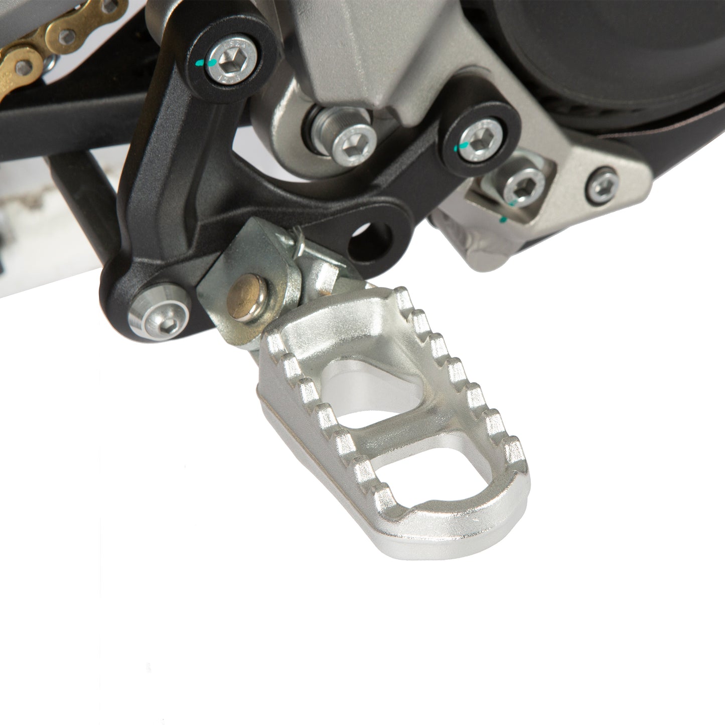 Close-up of a motorcycle foot peg with chain and sprocket in the background