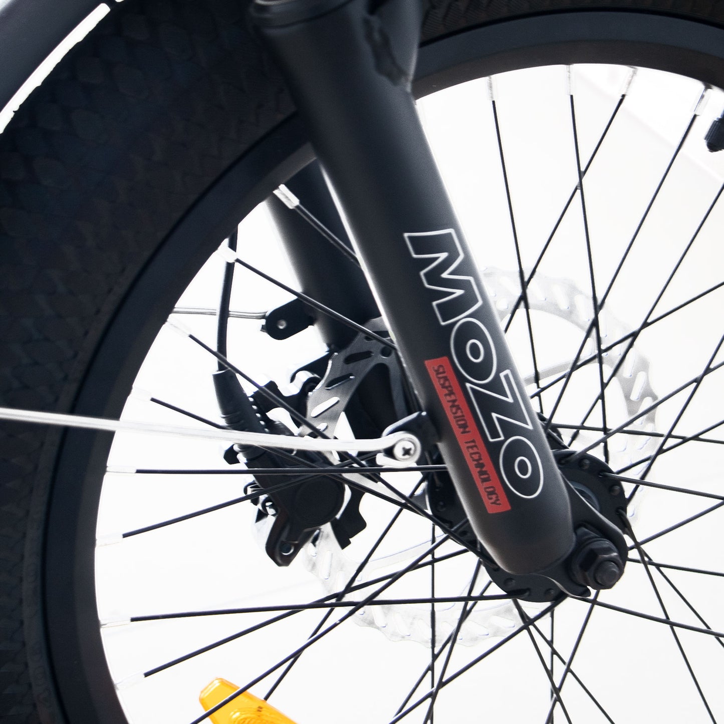 Close-up of a bicycle wheel with 'MOZO' branding on the suspension fork.
