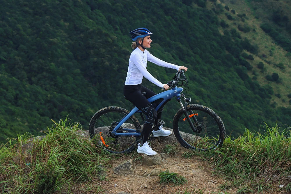 Person riding a bicycle on a mountain trail with a scenic background