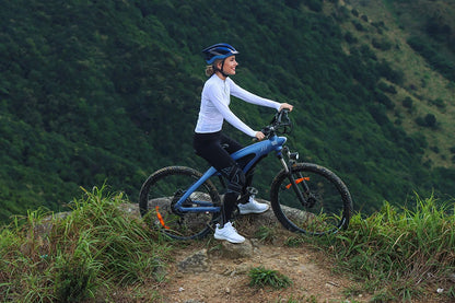 Person riding a bicycle on a mountain trail with a scenic background