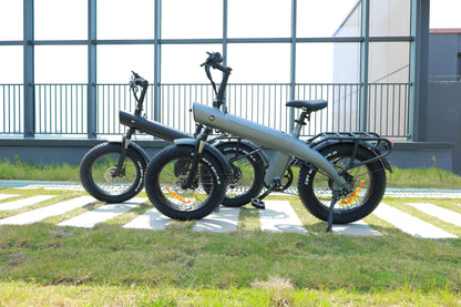 Three electric bicycles parked on a grassy area with a building in the background