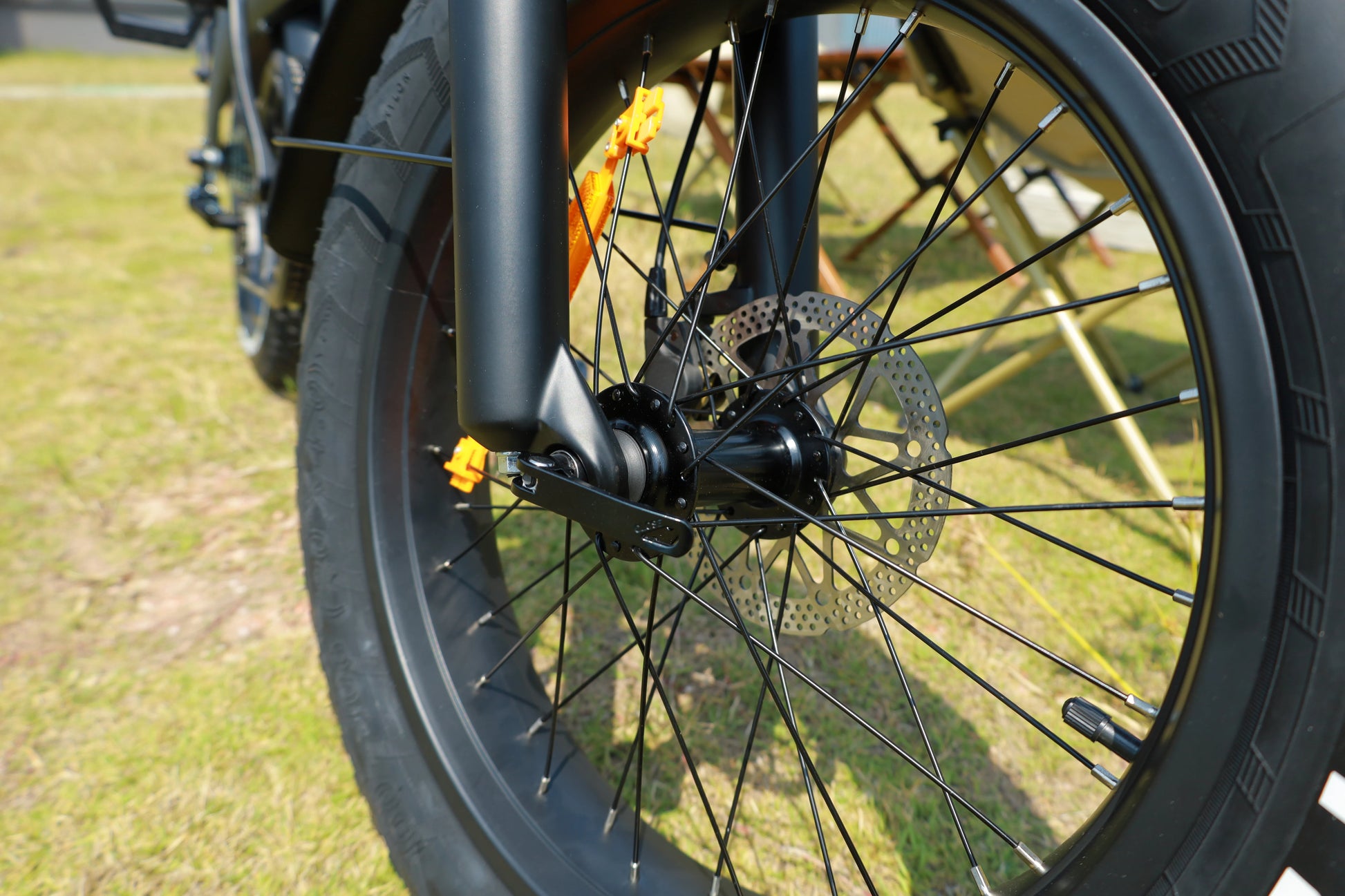 Close-up of a bicycle wheel with grass in the background