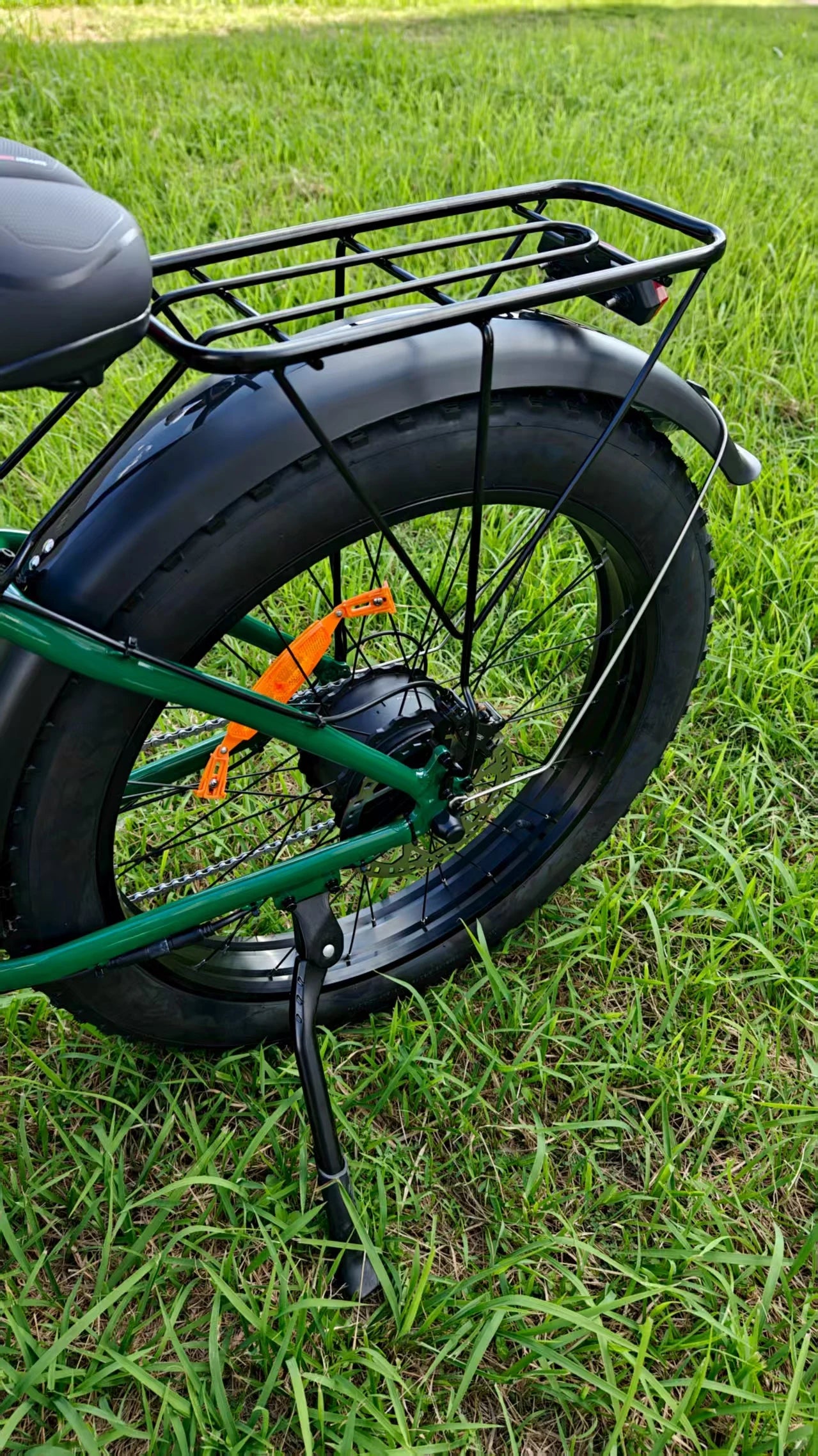 Close-up of a bicycle wheel with a black tire and green frame on grass.