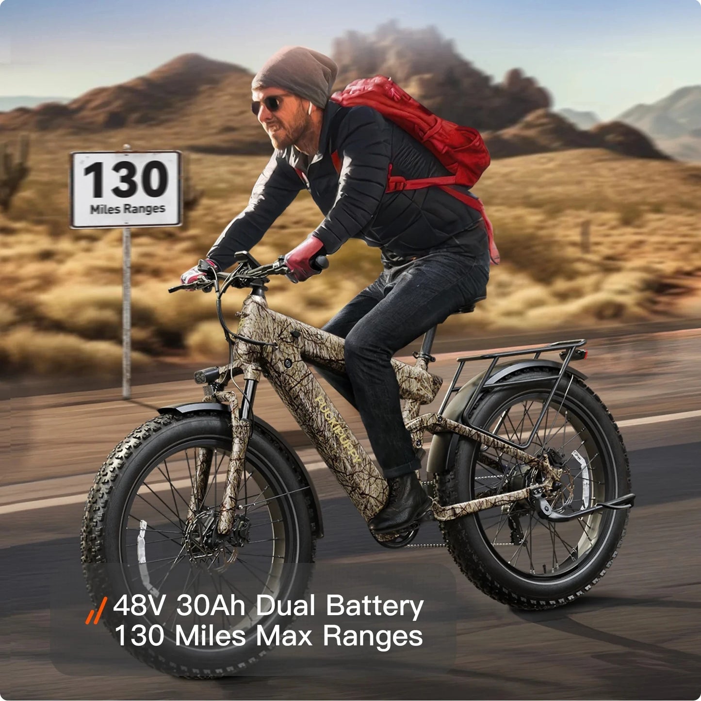 Person riding an electric bike in a desert setting with a sign indicating battery range.