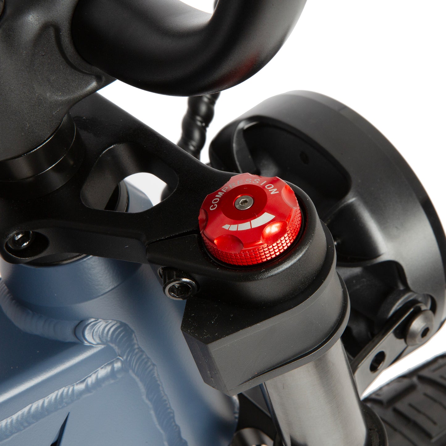 Close-up of a motorcycle suspension system with a red cap on a white background